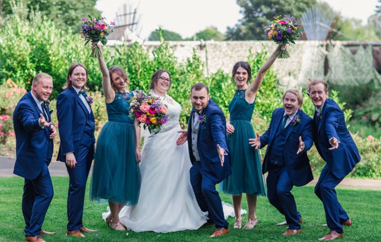 Bride and groom with bridesmaids and groomsmen cheering