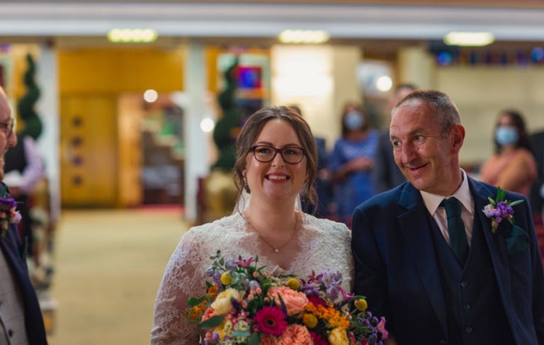 Bride smiling walking down the aisle with her father