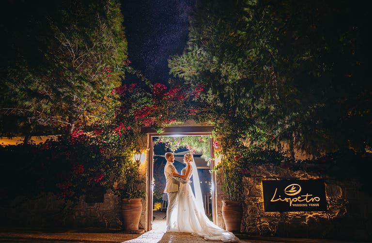 Katie and James embracing outside their wedding venue while the sun has gone down