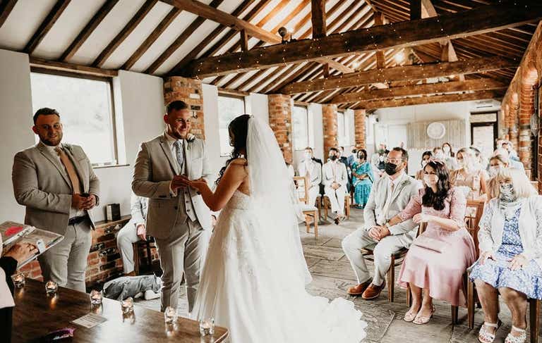Bride and groom smiling holding hands during ceremony