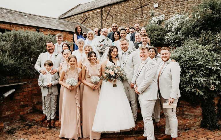Bride and groom stood outside venue with bridal party
