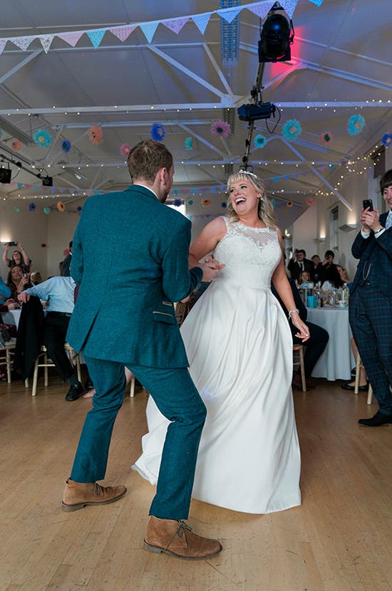 Bride and Groom smiling and dancing while their guests watch on