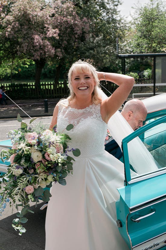 Bride getting out of the wedding car holding her wedding bouquet