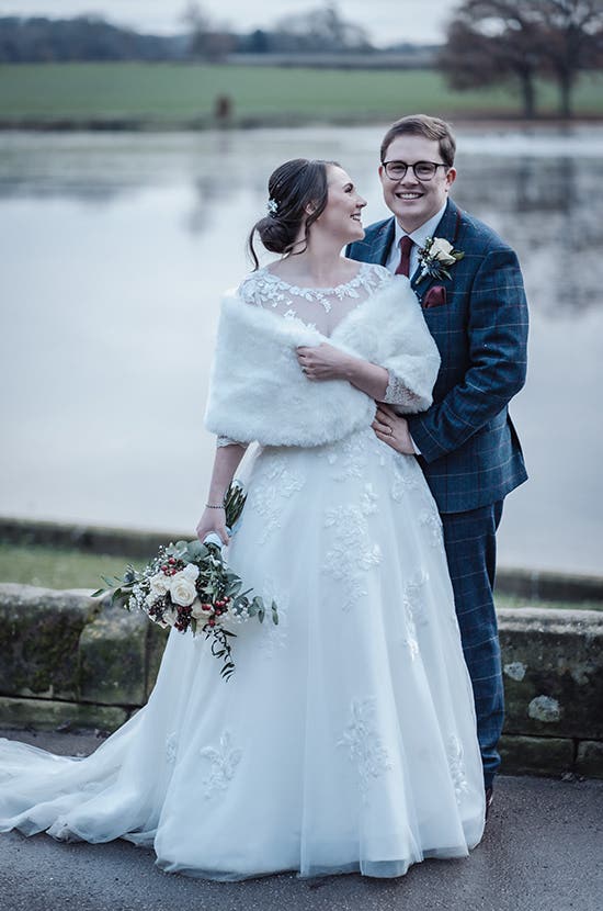 Rhiannon wearing a fur shrug posing with Edward in the grounds of their venue