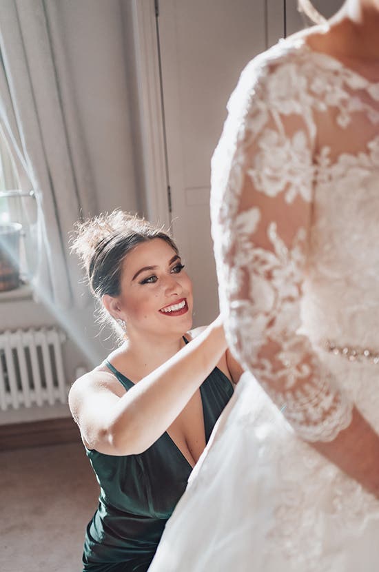 Rhiannon's bridesmaids helping to fasten her wedding dress