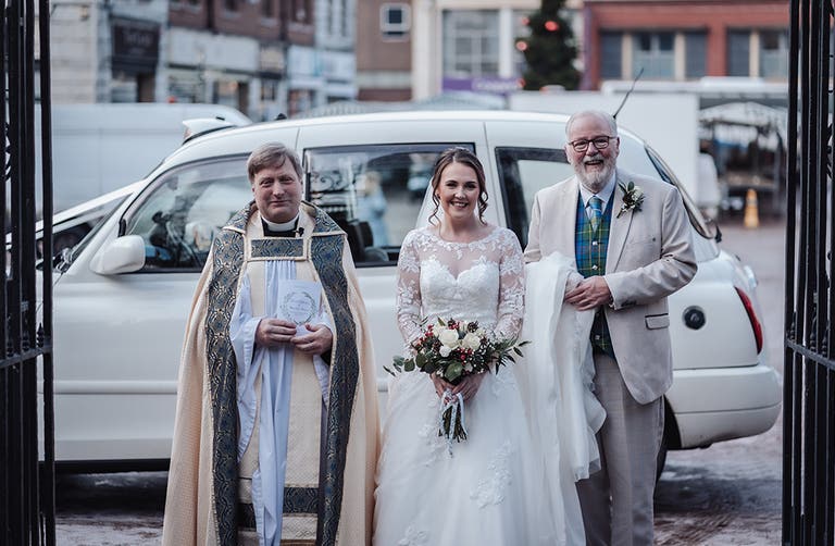 Rhiannon and her dad posing outside the church with the priest