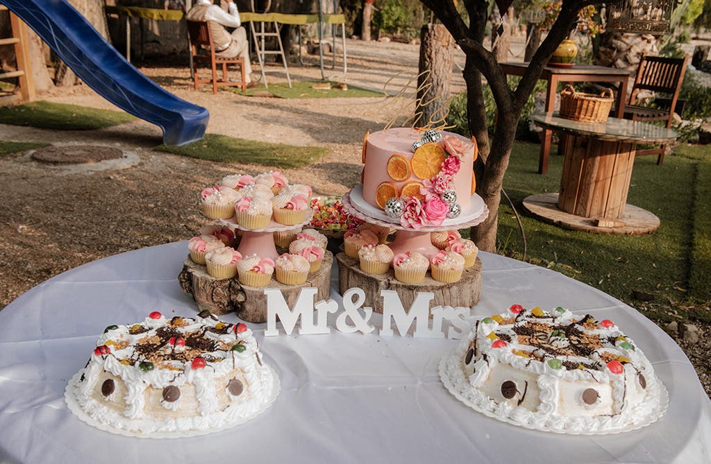Wedding cake table with cupcakes and colourful decor at Amy and Rob’s Spanish villa wedding