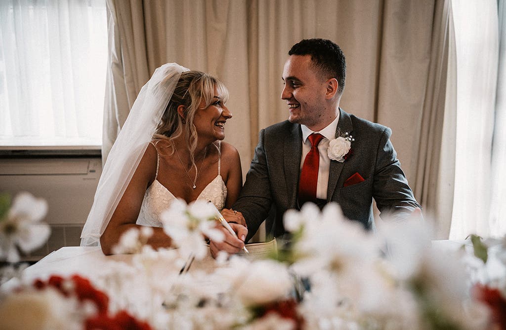 Sophie and Dean smiling at each other during their wedding ceremony