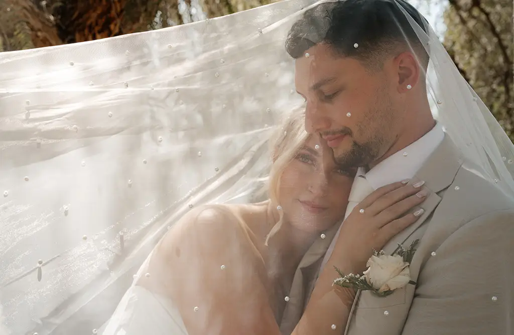 Close-up of Amy and Rob embracing under her wedding veil during their outdoor ceremony