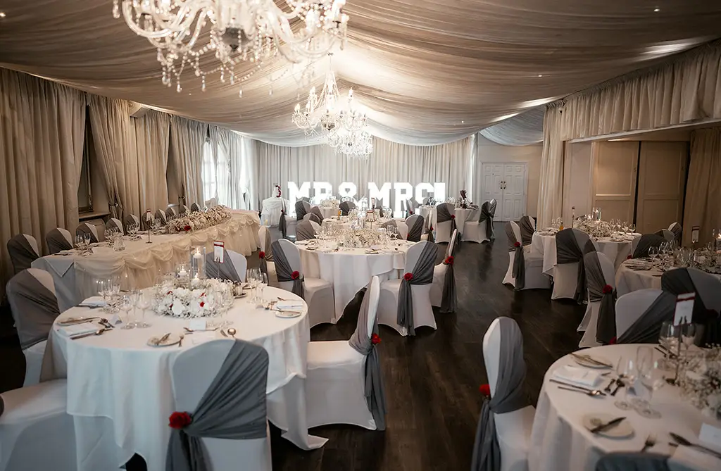 Wedding reception styling with grey chair sashes and red floral details