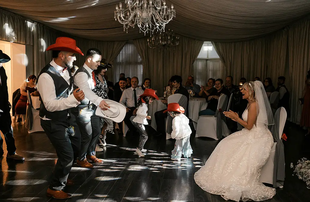 Dean and guests performing a choreographed dance wearing cowboy hats