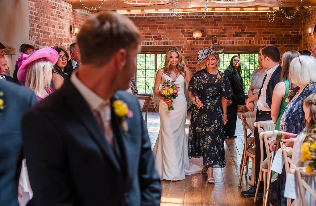 Bride walking down the aisle at a spring barn wedding