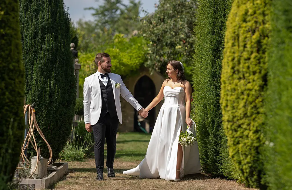 Lottie and Jonas walking through the wedding venue grounds holding hands and looking at each other