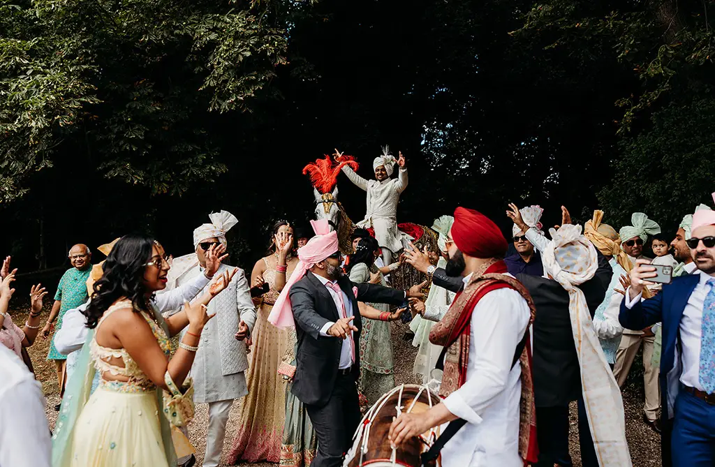 Ronit celebrating with wedding guests during the Baraat procession outside Ragley Hall