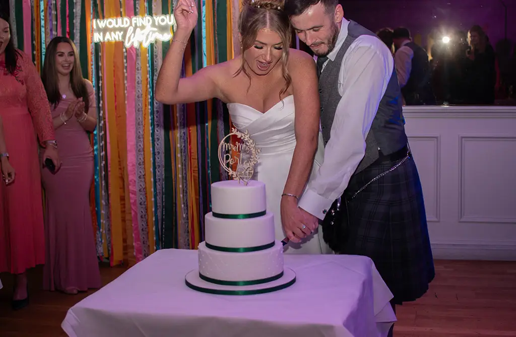 Daisey and Kieran cutting their wedding cake