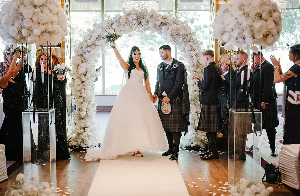 Kristeen and Ryan during their wedding ceremony with Kristeen raising her bouquet