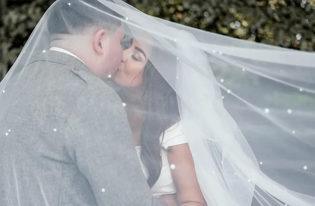 Joanna and Joseph kissing under Joanna’s wedding veil