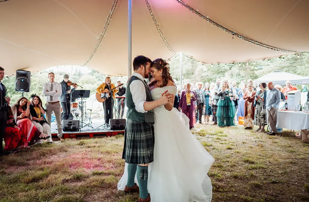 Sarah-Jane and Stephen dancing under their tipi with wedding guests watching