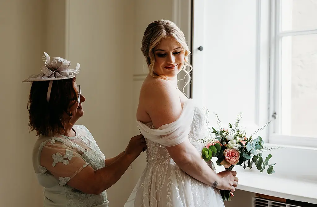 Fran in her wed2b Jana gown while her mum fastens the back of the dress