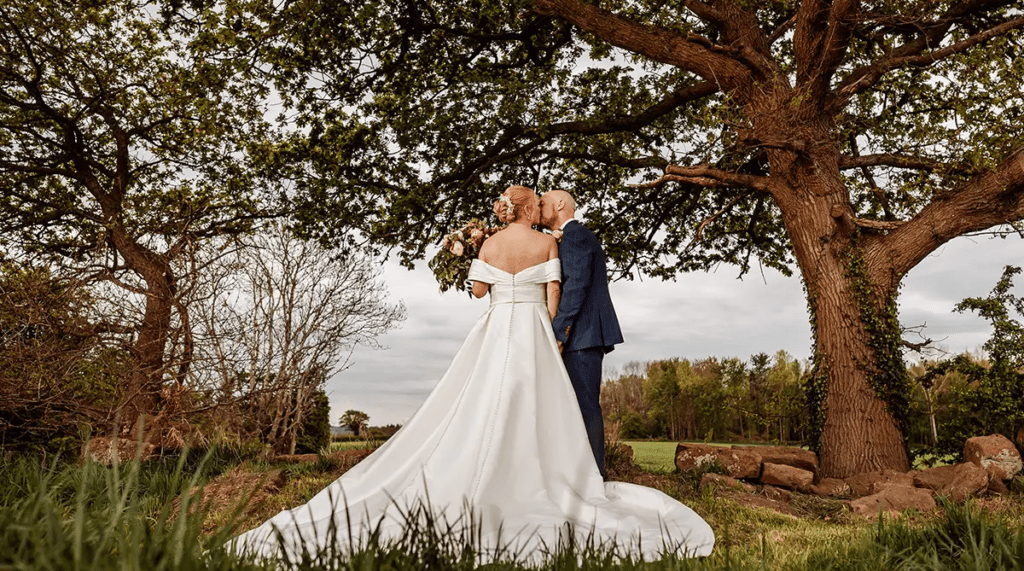 Catherine and Mike kissing with a scenic countryside view behind them on their wedding day