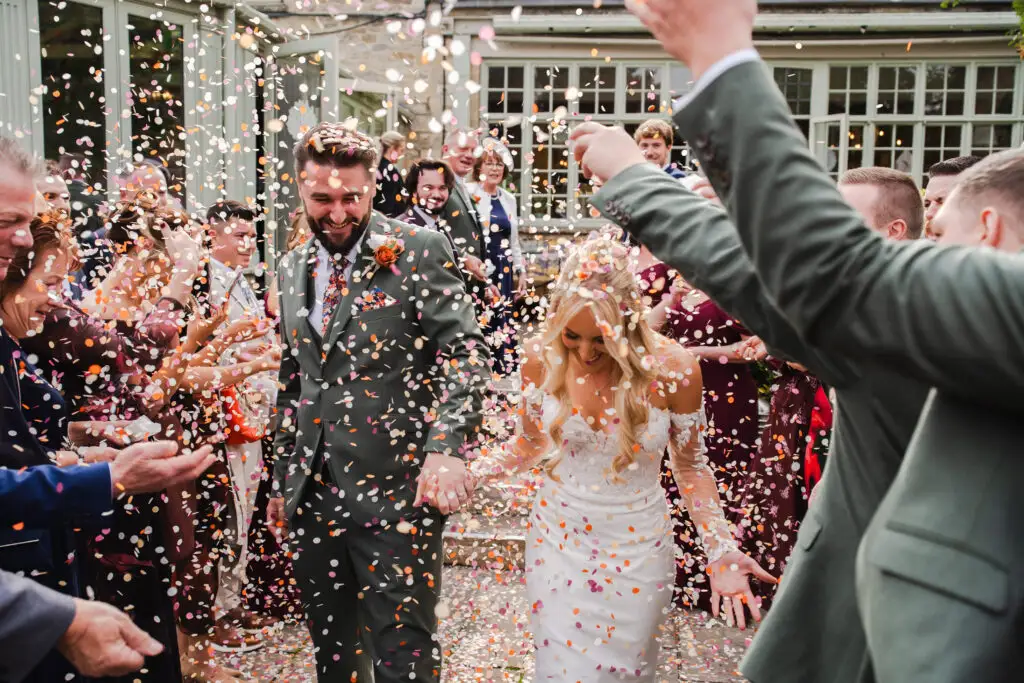Jaynie and Jack at their Cotswold autumn wedding with confetti thrown after their ceremony
